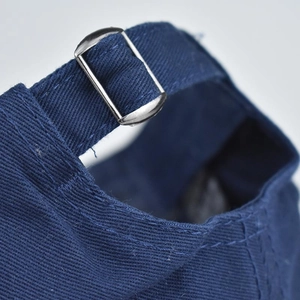 Détail de la boucle métallique ajustable et du tissu en coton bleu marine d'une casquette