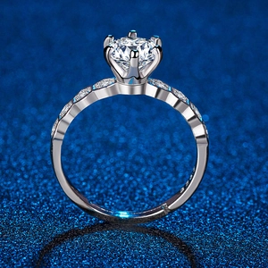 Macro shot of silver six-prong engagement ring with side-stone accents on blue starry background