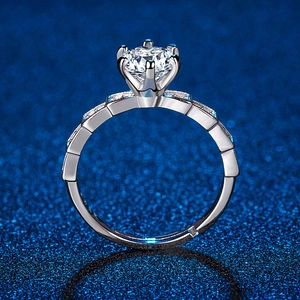 Macro view of six-prong moissanite ring with wavy diamond-set band on a dark blue base