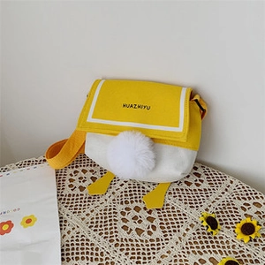 Detailed shot of yellow and white canvas crossbody bag with navy collar lid and duck feet charm