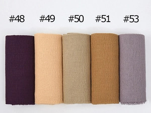 Close-up of pleated cotton scarves in purple, beige, khaki, and brown color options