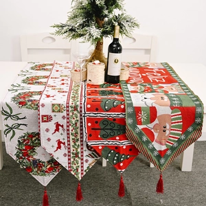 Festive knitted Christmas table runners with deer, trees, and red tassels on a white table