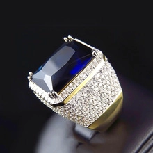 Macro view of men's gold ring with a large blue rectangular gemstone and white diamonds