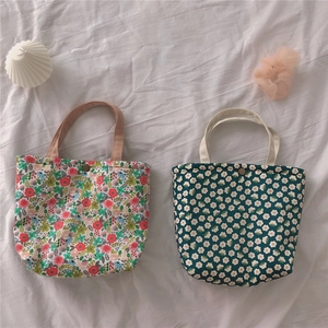 Close-up of floral bento bags with retro metal buttons on white wrinkled fabric