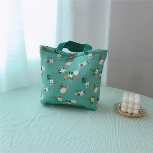 Close-up of floral quilted tote bag with green ribbon handle and secure metal snap button