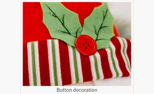 Detail of Christmas tree hugger featuring a red button and green felt holly leaf textures