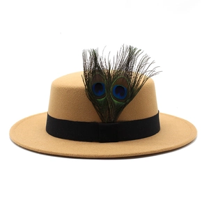 Detail of camel wool boater hat with black ribbon and two natural peacock feathers
