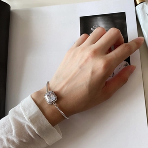 Detail of 925 silver bracelet with large square zircon worn on a wrist against a magazine