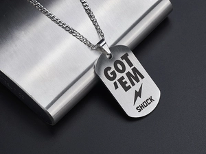 Detailed close-up of a polished silver dog tag pendant with GOT EM SHOCK engraving