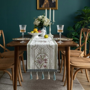 Elegant floral chenille table runner with tassels on a wooden dining table