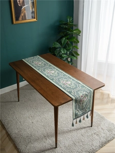 Close-up of vintage green chenille table runner with floral pattern and tassels