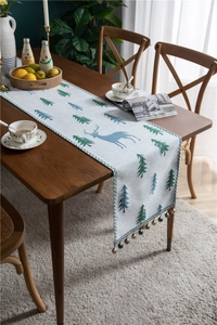 Close-up of chenille table runner featuring forest pine trees and blue deer with tassels