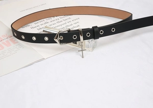 Détail d'une ceinture fine noire avec boucle en argent, œillets et pendentif croix