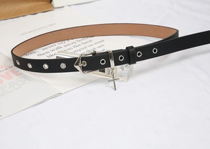 Détail d'une fine ceinture noire à boucle ardillon argentée et pendentif en croix