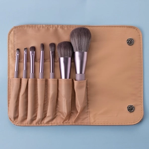 Detail of 8 purple metallic makeup brushes stored in a beige fabric travel organizer pouch