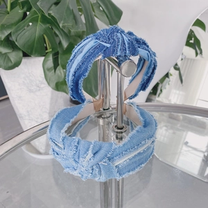Détail de bandeaux en jean torsadé bleu avec bords effilochés sur un support