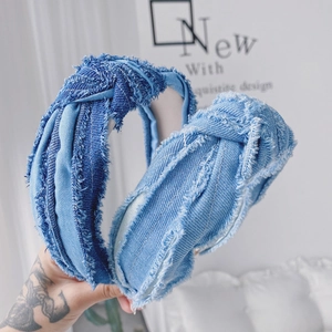 Gros plan du serre-tête en denim plissé avec bords effilochés et nœud central