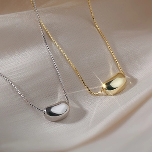 Minimalist gold and silver stainless steel bean pendant necklaces on champagne silk