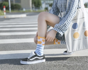 Mid-calf cotton socks with blue stripes and yellow patterns shown in a street style view