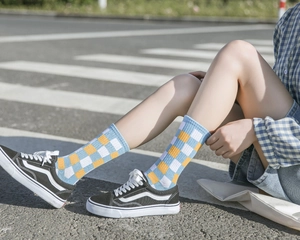 Blue yellow white checkered crew socks for women on feet in street setting