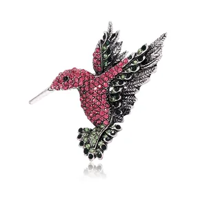 Sparkling hummingbird brooch with pink and green rhinestones on a polished metal base