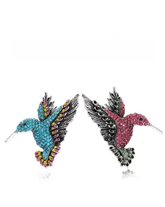 Detailed view of two hummingbird brooches with vibrant rhinestones on white background