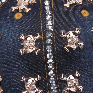 Macro detail of golden skull charm and rhinestones on blue denim baseball hat