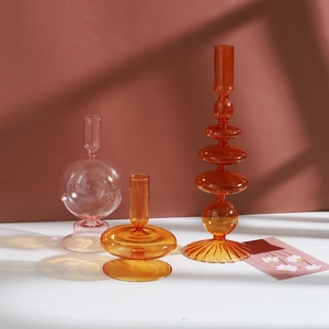 Série moderne de bougeoirs artistiques en verre ambré et rose sur une table minimaliste
