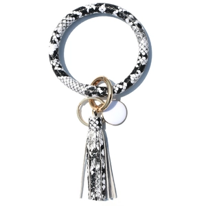 Close-up of black and white snakeskin PU leather bangle keychain with golden ring and tassel