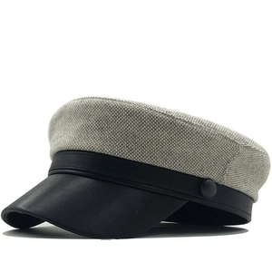 Detailed view of grey textured wool fabric and black leather brim on the newsboy cap