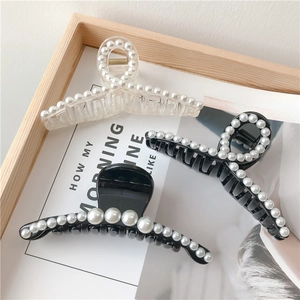 Detail of elegant pearl hair claws in transparent and black finishes on a tray