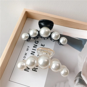 Close-up of large white pearls on black and clear resin hair claws in a Korean style