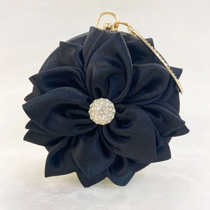 Close-up of black silk satin evening bag with 3D floral petals and rhinestone center