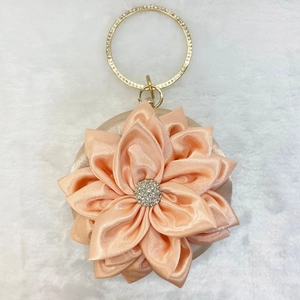 Detailed macro view of champagne silk round evening bag with large 3D fabric flower and crystal core