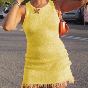 Detail of yellow sleeveless knit mini dress featuring chic tassel hem and slim fit
