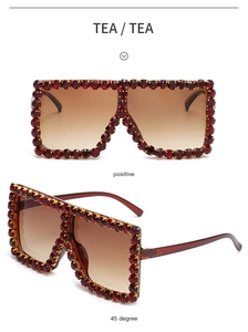 Detail view of oversized square sunglasses with red rhinestones and tea gradient lenses