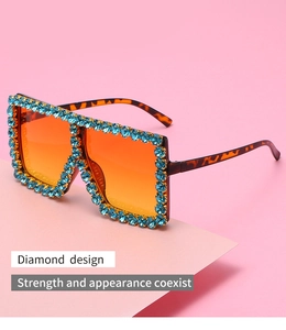 Macro detail of tortoise shell sunglasses with blue rhinestones and orange tinted lenses