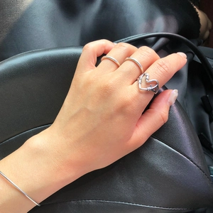 Detail shot of 925 silver knotted heart ring and minimalist bangles on a dark background