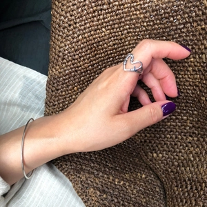 Knotted heart-shaped 925 sterling silver open ring shown on finger with warm background