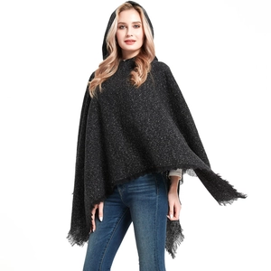 Detail of dark gray plaid poncho featuring textured knit, toggle button, and fringe edges