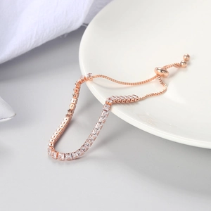 Rose gold adjustable tennis bracelet with 3mm square-cut crystals on white ceramic dish