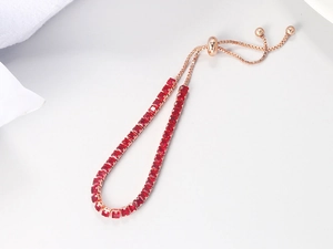 Detail of adjustable rose gold bracelet featuring a row of square red crystals with slide clasp