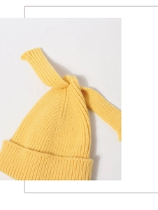 Close-up of yellow knit baby beanie with rabbit ear bow and soft ribbed texture