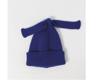 Detail of dark blue knitted baby hat texture with long decorative bunny ear knot tie
