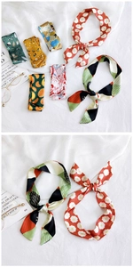 Flat lay of colorful floral silk scarves with glasses and books on white fabric