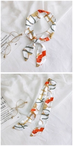Detail of silk scarf with nautical anchor patterns tied on a white fabric surface