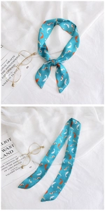 Detailed view of blue silk scarf with orange koi carp print tied in a bow on white fabric