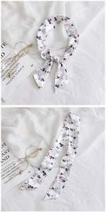 Detail of long skinny silk scarf with colorful cartoon bear prints on a white background