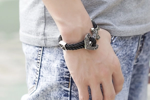 Close-up of men's black woven leather anchor bracelet with silver skull clasp on wrist