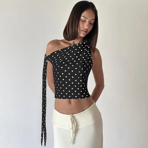Detail of a black polka dot one-shoulder top with a long elegant draped sash detail